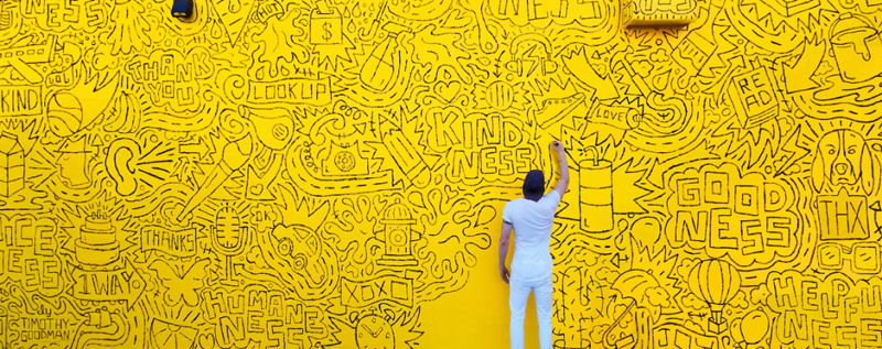 Timothy Goodman workiing on a large yellow mural